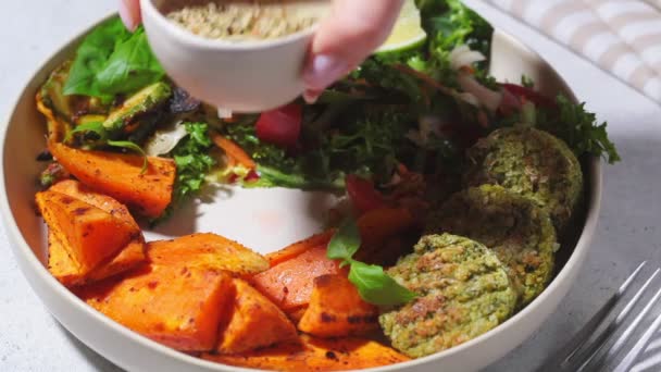 Falafel slakom. Veganistisch lunchbord - gebakken kikkererwtenkoteletjes met gebakken zoete aardappelen en groentesalade in wit bord. — Stockvideo