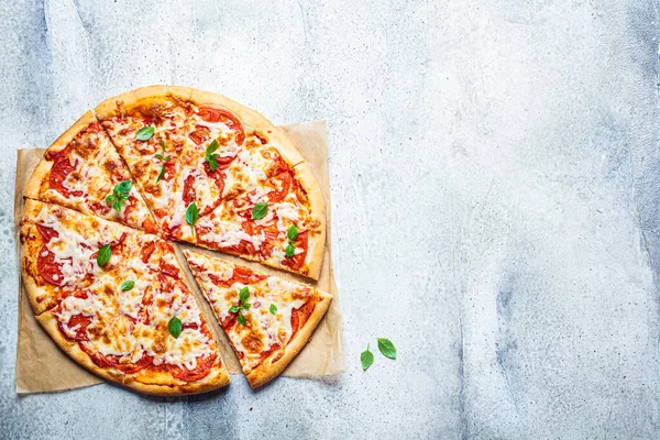 Classic pizza margarita with mozzarella, tomato and basil, gray background. Italian food concept.