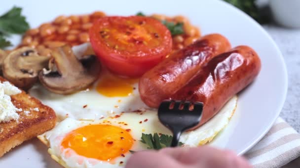 Colazione all'inglese con salsicce, fagioli, uova fritte, toast, funghi e pomodori. Concetto colazione inglese. — Video Stock