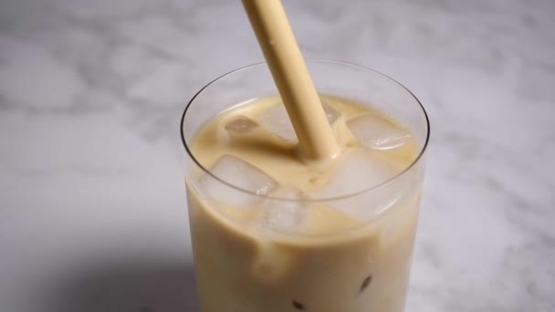 Café con leche helada en vidrio con paja de madera. concepto de bebidas de verano. — Vídeos de Stock