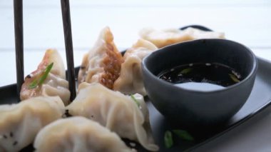 Soslu kızarmış gyoza köftesi ve siyah tabakta yeşil soğan.. 