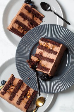 Gri bir tabakta böğürtlenli çikolatalı kek parçaları, beyaz mermer arka plan. Vejetaryen tatlı konsepti.