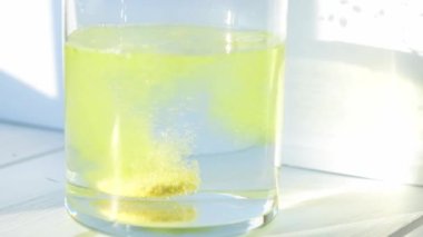 Şişirilmiş C vitamini kapsülü, bir bardak su, yakın plan, beyaz arka plan. Sağlık konsepti vitaminleri.
