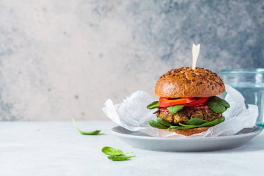 Fırında patates, domates sosu ve gri tabakta taze sebzeli vejetaryen mercimek burgeri. Vejetaryen gıda konsepti.