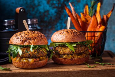 Roka soslu vejetaryen mercimek burger, hardal sosu, taze sebze ve tahtadan yapılmış patates kızartması. Vejetaryen gıda konsepti.