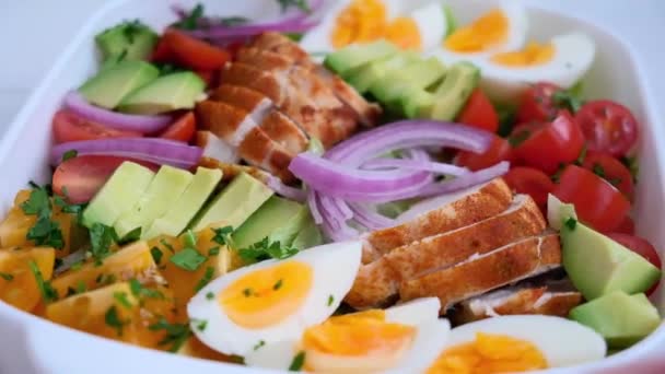 American cobb salad with chicken, avocado, egg, tomatoes and onions in white dish. American cuisine concept. — Stock Video