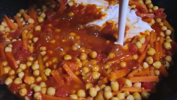 Veganes Kichererbsencurry im schwarzen Wok kochen. Kokoscreme in das Curry gießen. — Stockvideo