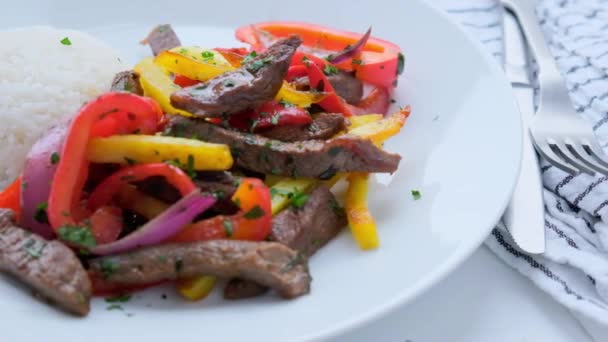 Peru mutfağı konsepti. Lomo saltado - Biberli kızarmış biftek, soğan, patates ve pilav. — Stok video