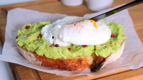 Toast à l'avocat avec oeuf poché sur planche de bois. — Video