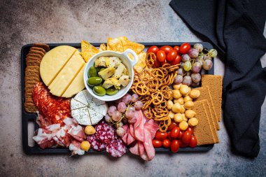 Şarküteri ve peynir tabağı. Çeşit çeşit et, peynir, meyve, zeytin ve krakerle aperatif tepsisi..