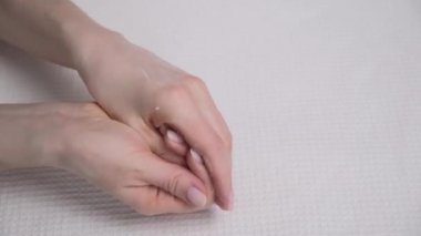 Kadın beyaz arka planda krem sürerek ellerin kuru cildini lekeler..