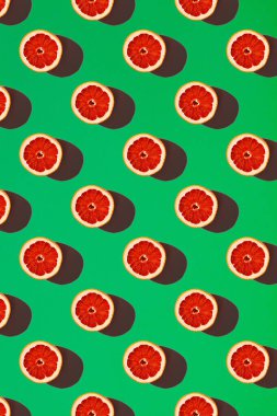 Yeşil arka planda kırmızı greyfurt yarıları. Gıda modeli konsepti.