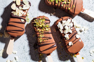 Badem, hindistancevizi ve gri arka planda fıstık serpiştirilmiş çikolatalı dondurma. Siyah çikolatalı vejetaryen dondurması..