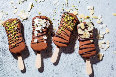 Badem, hindistancevizi ve gri arka planda fıstık serpiştirilmiş çikolatalı dondurma. Siyah çikolatalı vejetaryen dondurması..