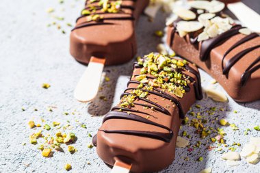 Badem, hindistancevizi ve gri arka planda fıstık serpiştirilmiş çikolatalı dondurma. Siyah çikolatalı vejetaryen dondurması..