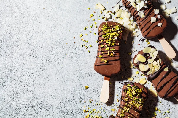 Badem, hindistancevizi ve gri arka planda fıstık serpiştirilmiş çikolatalı dondurma. Siyah çikolatalı vejetaryen dondurması..