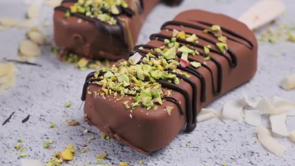 Helado de chocolate helado espolvoreado con almendras, coco y pistachos, de cerca. Helado vegano en chocolate negro. — Vídeo de stock