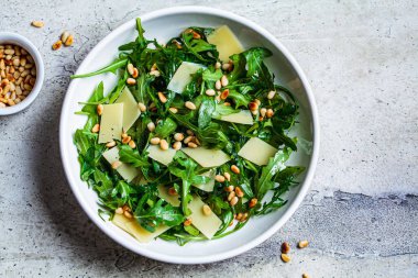 Arugula ve beyaz kasede çam fıstığı ile parmesan salatası. İtalyan mutfağı kavramı.