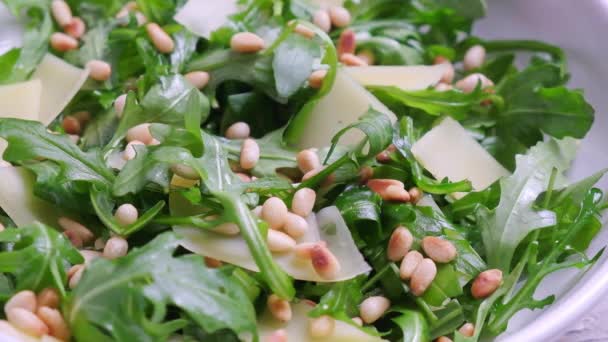 Arugula and parmesan salad with pine nuts in white bowl. — Stock Video