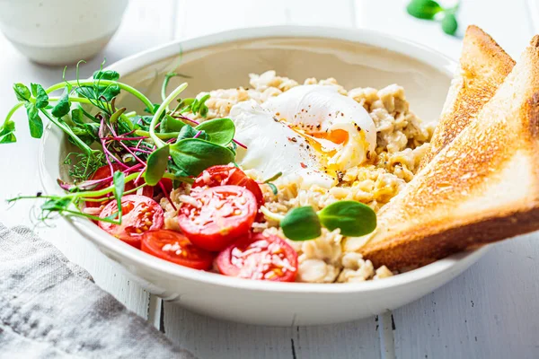 味道鲜美的燕麦片 配上煮熟的鸡蛋 西红柿 奶酪和白碗中的芽 健康早餐概念 — 图库照片