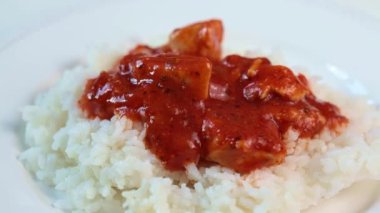 Domates soslu kızarmış tavuk ve beyaz tabakta pilav.