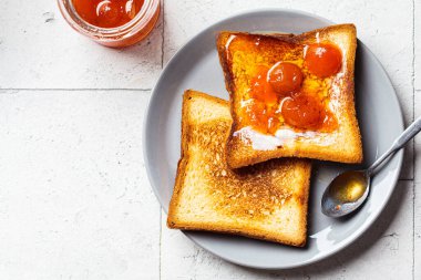 Gri tabakta tereyağlı tost ve kayısı reçeli. Kahvaltı konsepti..