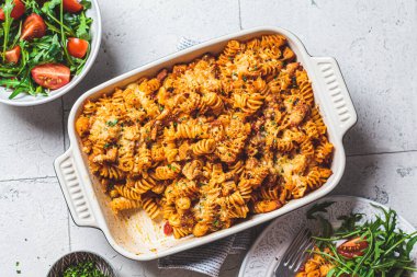 Fırında tavuk ve peynirli fırında makarna, gri arka plan. İtalyan mutfağı kavramı.