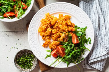 Beyaz tabakta tavuk ve peynirli fırında makarna, gri arka plan. İtalyan mutfağı kavramı.