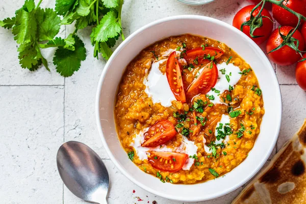 Vegan lentil soup with cilantro and tomatoes, copy space. Dal soup with tomatoes. Indian cuisine concept.