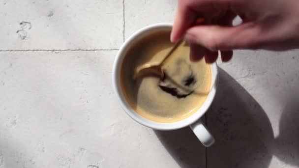 Белая чашка черного кофе, перемешать сахар ложкой, вид сверху. — стоковое видео