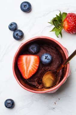 Beyaz mermer arka planda pembe bir fincanda böğürtlenli çikolatalı kek. Hızlı vejetaryen mikrodalga tarifi.