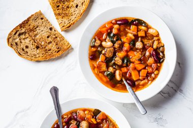 Beyaz tabakta sosisli fasulye çorbası, beyaz mermer arka plan. İtalyan mutfağı kavramı.