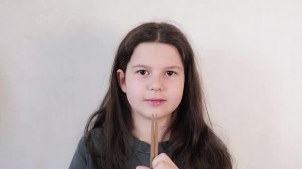 Adolescente con el pelo largo se prepara para comer sushi y toma palillos, fondo de pared clara. concepto de comida japonesa. — Vídeos de Stock