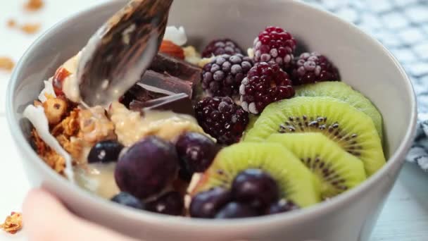 Overnachting havermout kom met kiwi, chocolade, bessen en tahini, eten, close-up. — Stockvideo