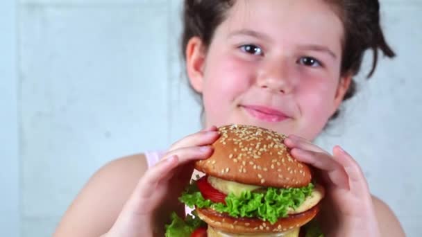 Brunett tonåring flicka äter stora vegan hamburgare. — Stockvideo