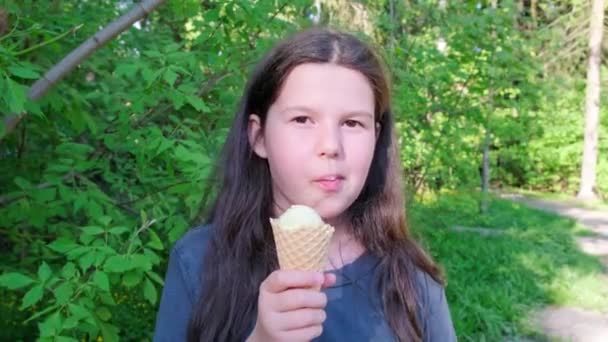 Brunette girl eating an ice cream cone in summer park. — Stock Video