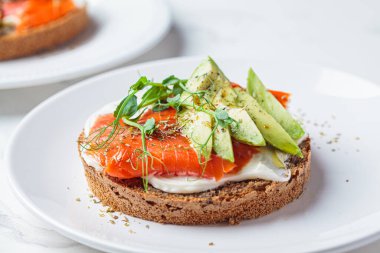 Krem peynirli tost, somon balığı ve avokado, beyaz arka plan. Keto diyet kavramı.