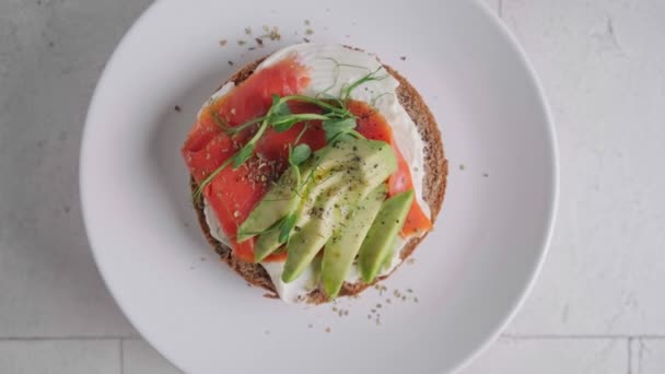 Тост на завтрак со сливочным сыром, лосось и авокадо, белый фон. — стоковое видео