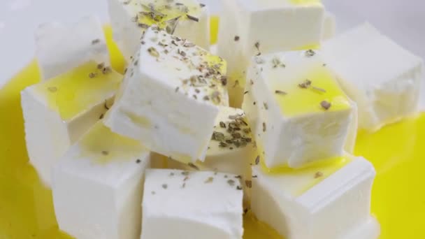 Ser feta z oliwą z oliwek i suszonymi ziołami na białym talerzu. — Wideo stockowe