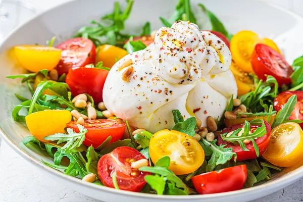 Burrata cheese salad with arugula and tomatoes. Italian cuisine concept.