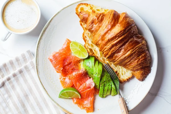 配上咸肉鲑鱼和鳄梨片在白盘上的羊角面包 上视图 烹调健康早餐的概念 — 图库照片