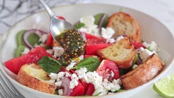 Kochen italienischer Salat mit Tomaten, Feta-Käse, gegrilltem Ciabatta und Senfdressing. — Stockvideo