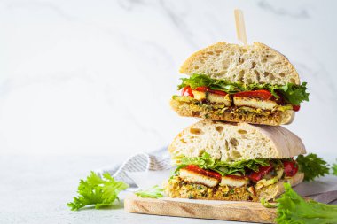 Vejetaryen sandviçi, ızgara sebze, halloumi peyniri ve ciabatta, beyaz arka plan, fotokopi alanı. Rahatlatıcı gıda konsepti.