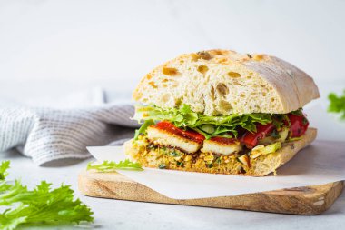 Vejetaryen sandviçi, ızgara sebze, halloumi peyniri ve ciabatta, beyaz arka plan, fotokopi alanı. Rahatlatıcı gıda konsepti.