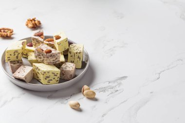 Gri bir plaka üzerinde beyaz mermer zemin üzerinde farklı türde halva parçaları. Orta doğu tatlı konsepti. Sağlıklı yiyecekler.