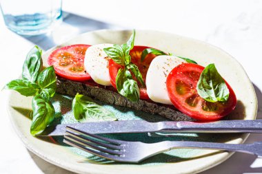 Beyaz mermer arka planda Caprese sandviçi. Mozzarella, domates ve fesleğenli tost. İtalyan mutfağı kavramı.
