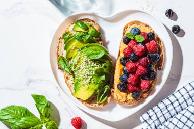 Fıstık ezmeli ve çilekli tost ve fesleğenli avokado tostu. Sağlıklı vejetaryen kahvaltı konsepti.