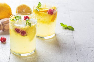 Naneli ev yapımı limonata ve gözlüklü ahududu, gri fayanslı arka plan, fotokopi alanı. Soğuk yaz içkisi konsepti.