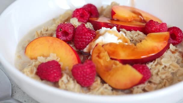 Summer oatmeal with raspberries, peaches and nuts. — Stok Video