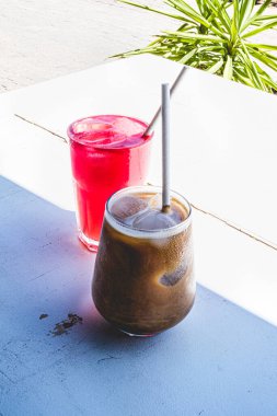 Buzlu karamel latte ve beyaz bir masada karpuz suyu, dikey. Yaz kahvesi..